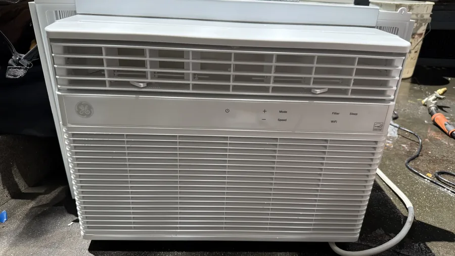 Window AC unit taken out of the opening and resting on the floor