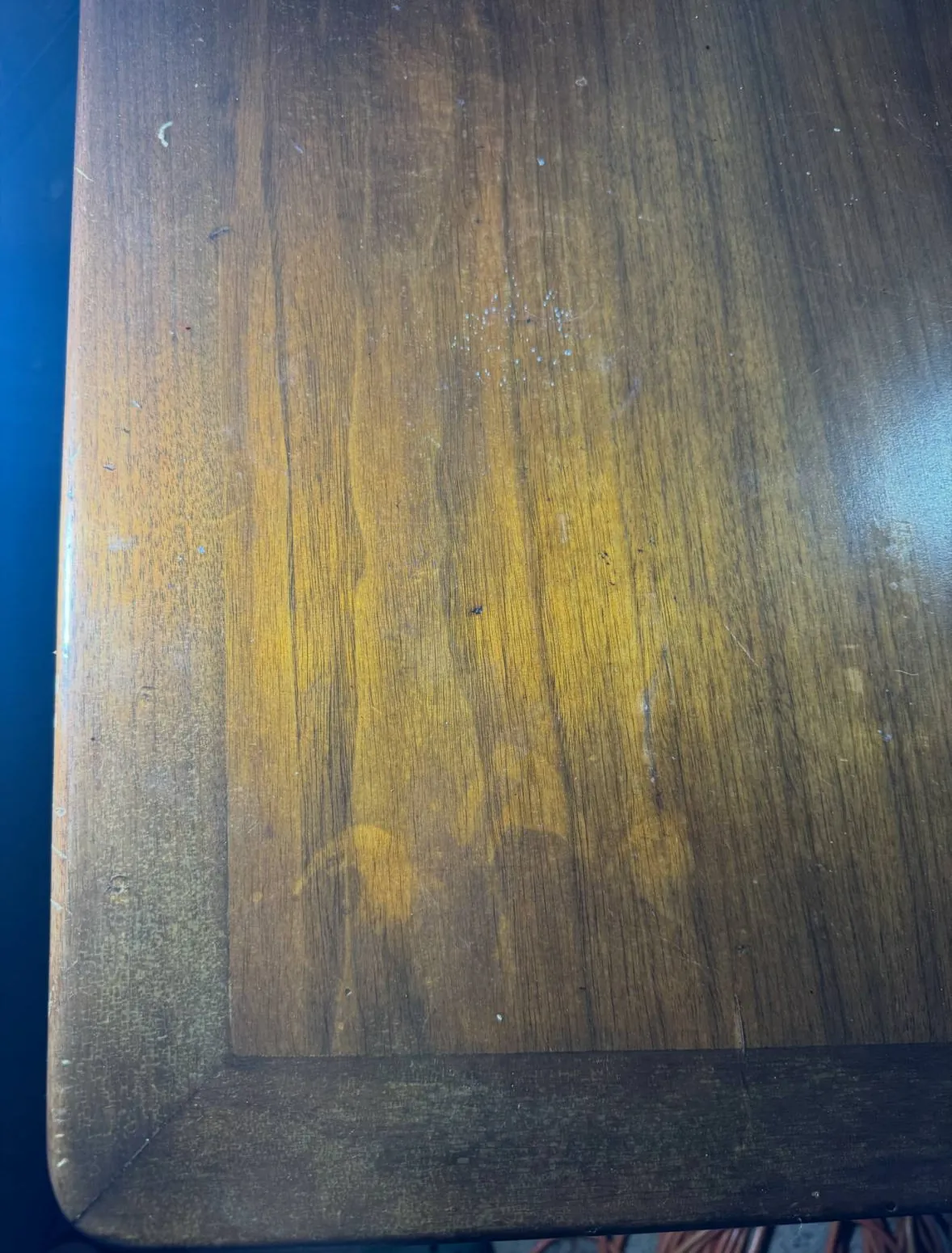 Before photo of cloudy blotchy spots in a soft polyurethane finish on a wood table corner