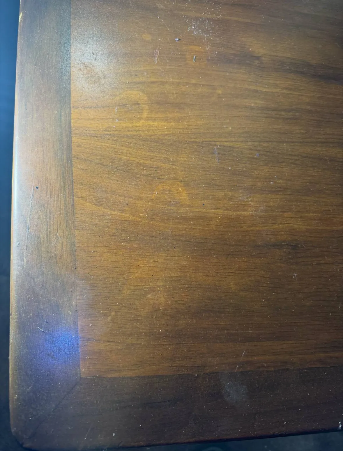 Before photo of faint rings and water marks left by everyday items on a sticky table finish