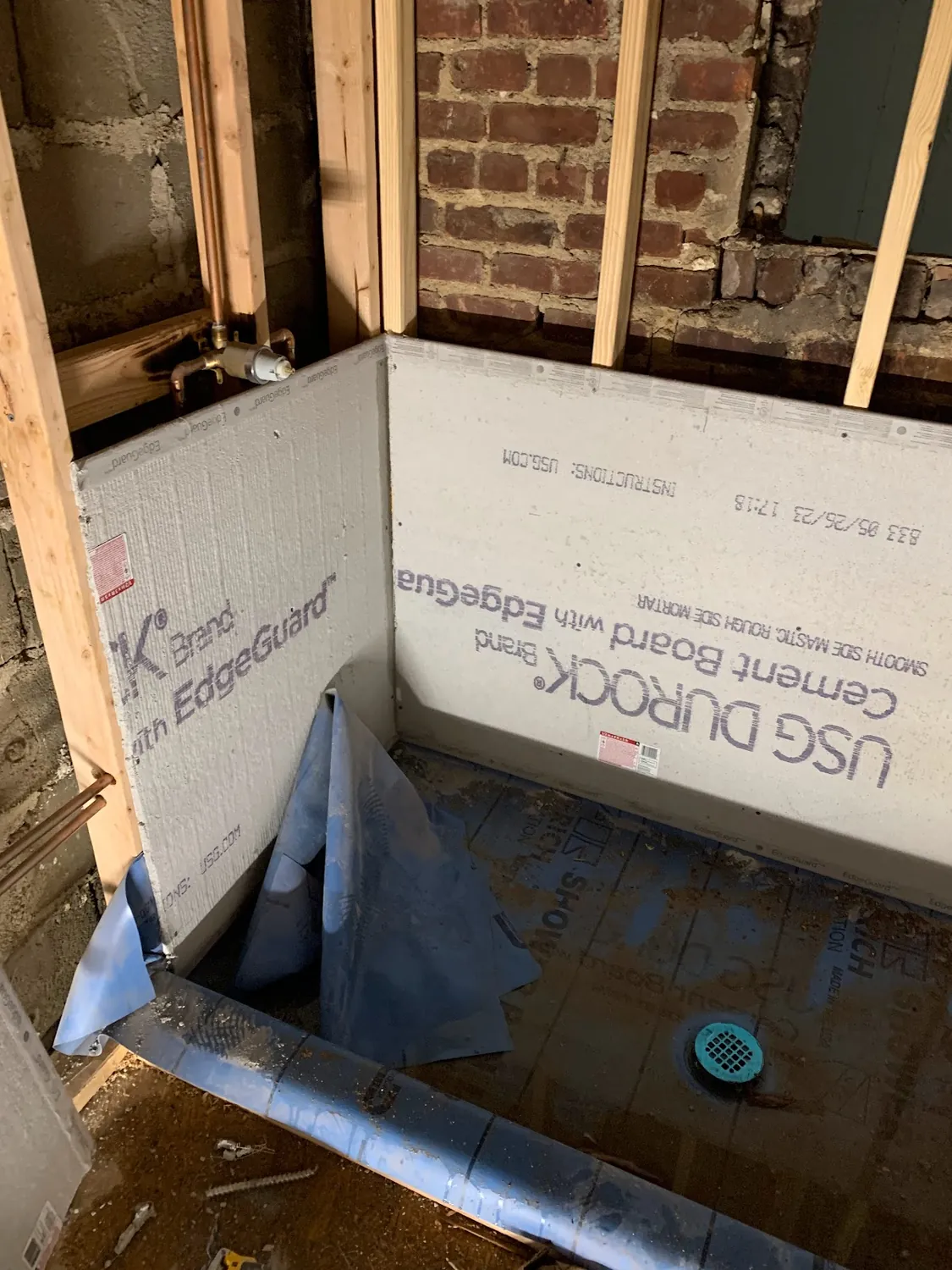 Cement backer board, blue waterproofing membrane, and a sloped shower pan with drain during the bathroom build-out