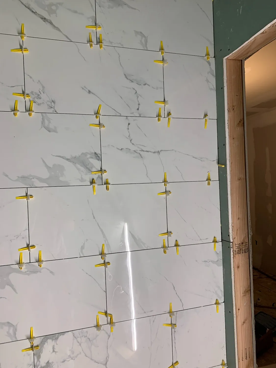 Large-format marble-look porcelain feature wall in a Queens bathroom