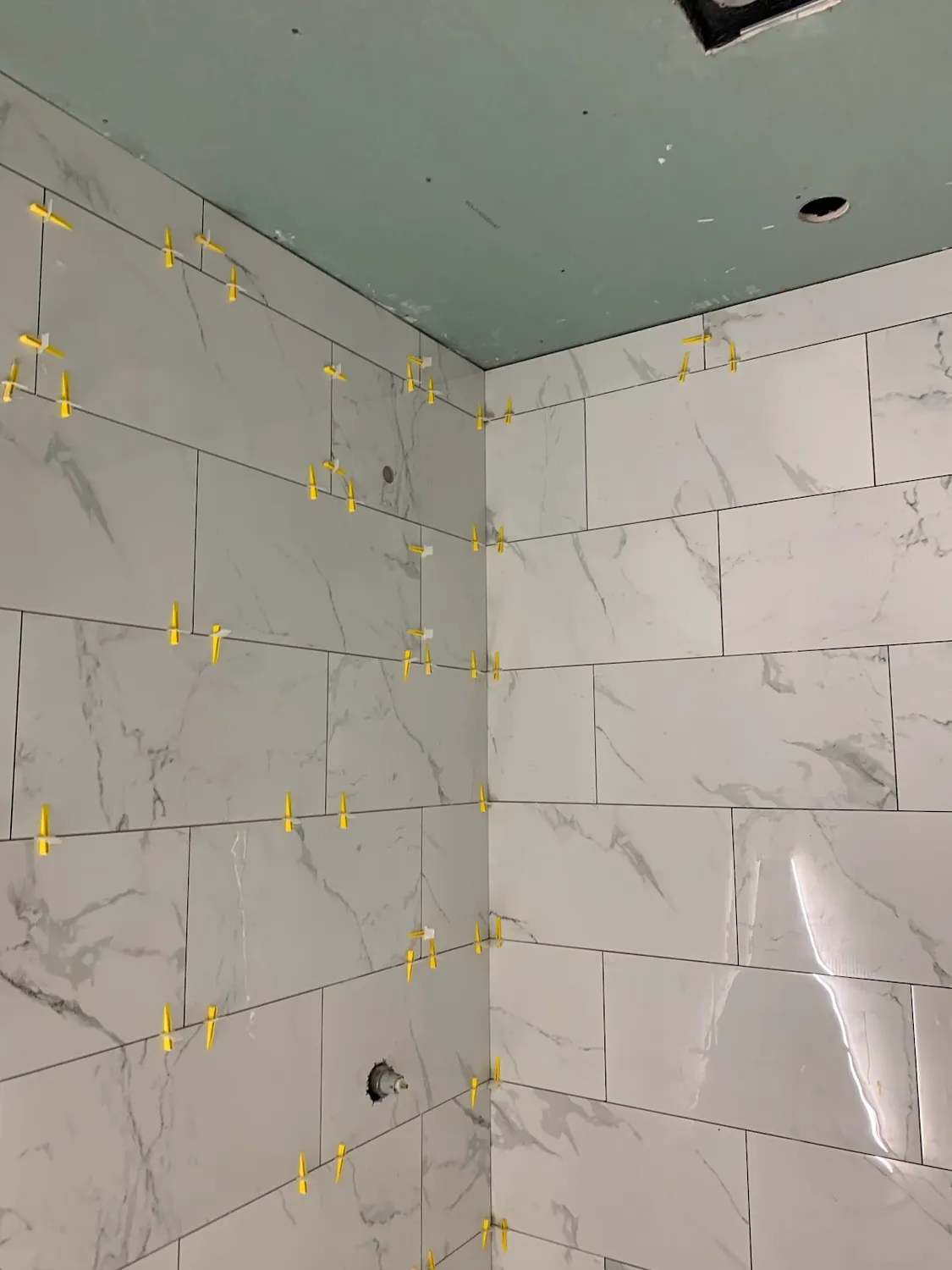 Large-format marble-look porcelain wall tile installed with leveling clips