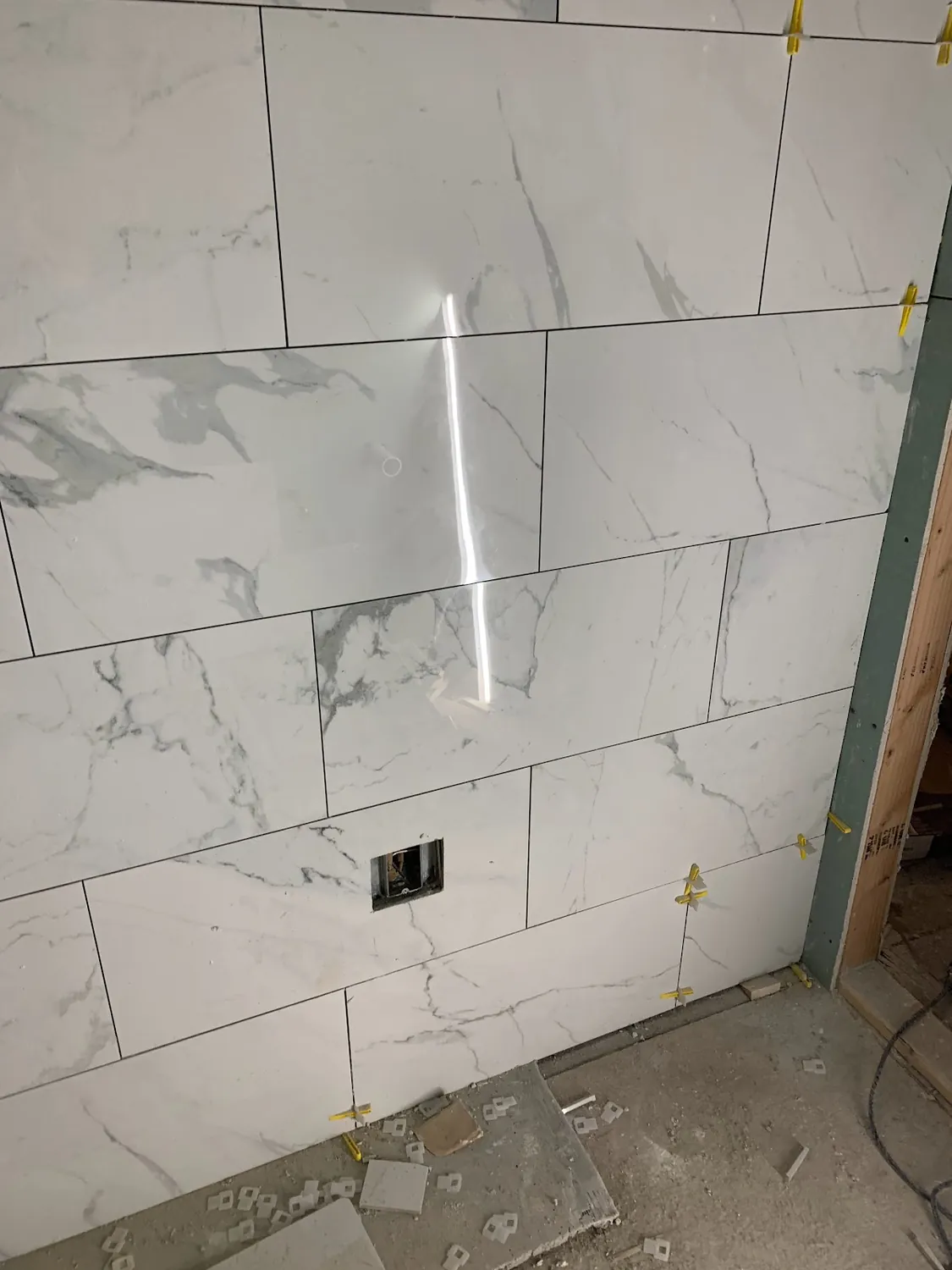 Marble-look porcelain wall tile fit cleanly around the shower valve