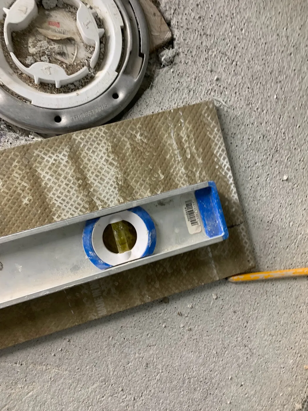 Checking the slope of the shower base to the drain with a level