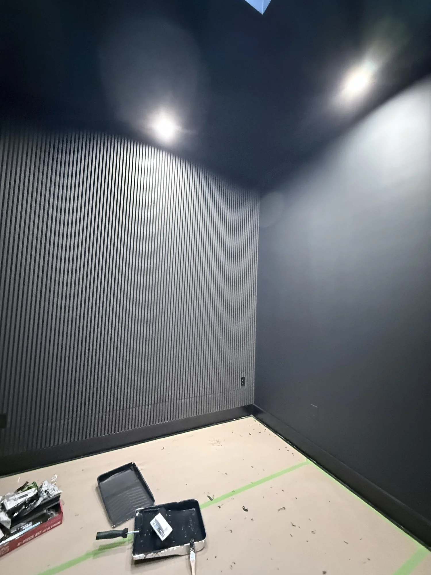 Finished wood slat accent wall against black walls and ceiling, Brooklyn