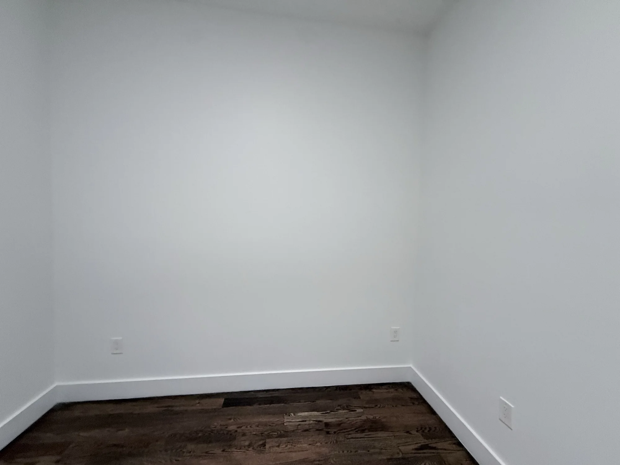 Empty white room corner with wood floor before the black paint job, Brooklyn