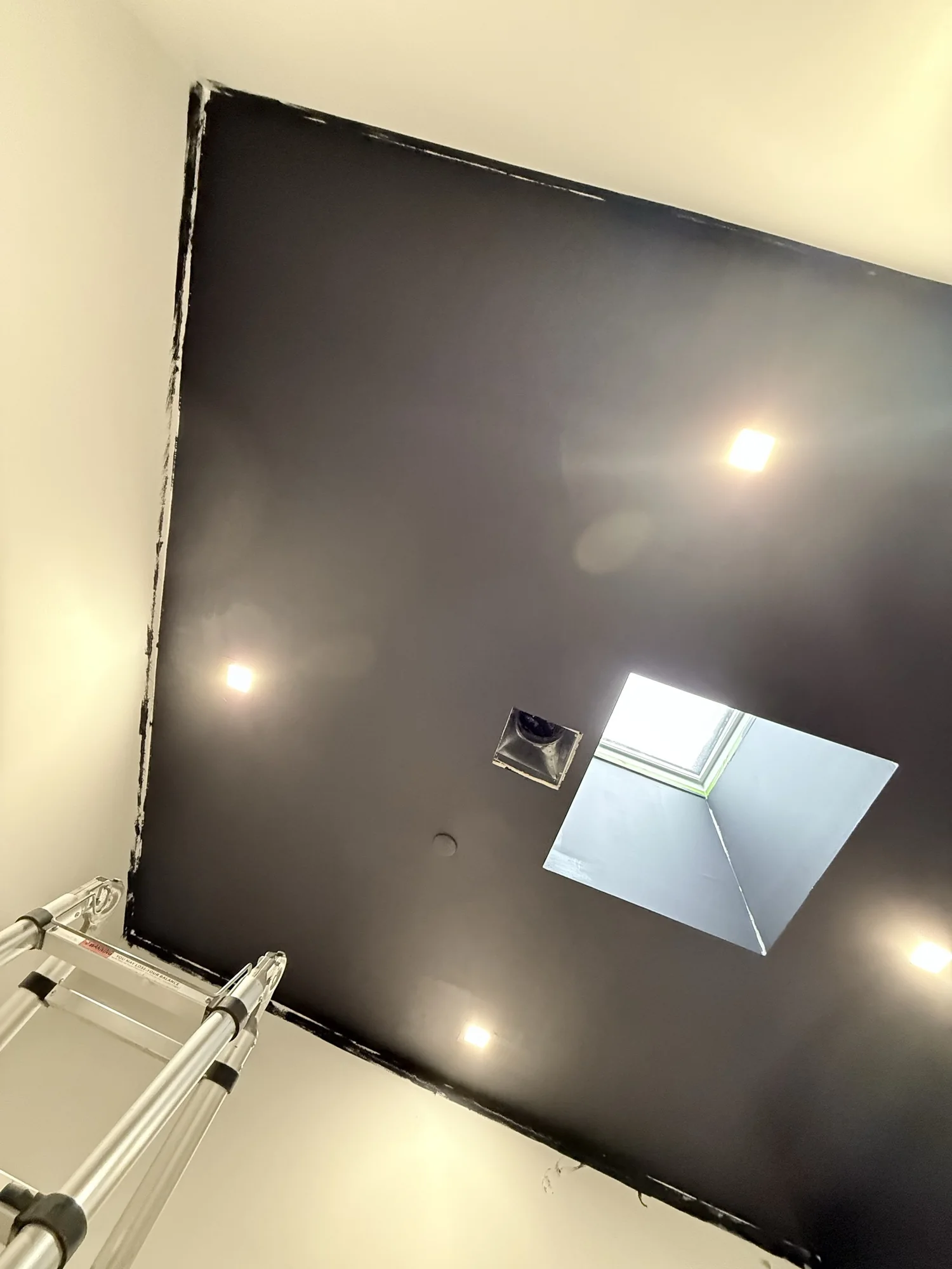 High-gloss black ceiling with a skylight, painted first before the walls