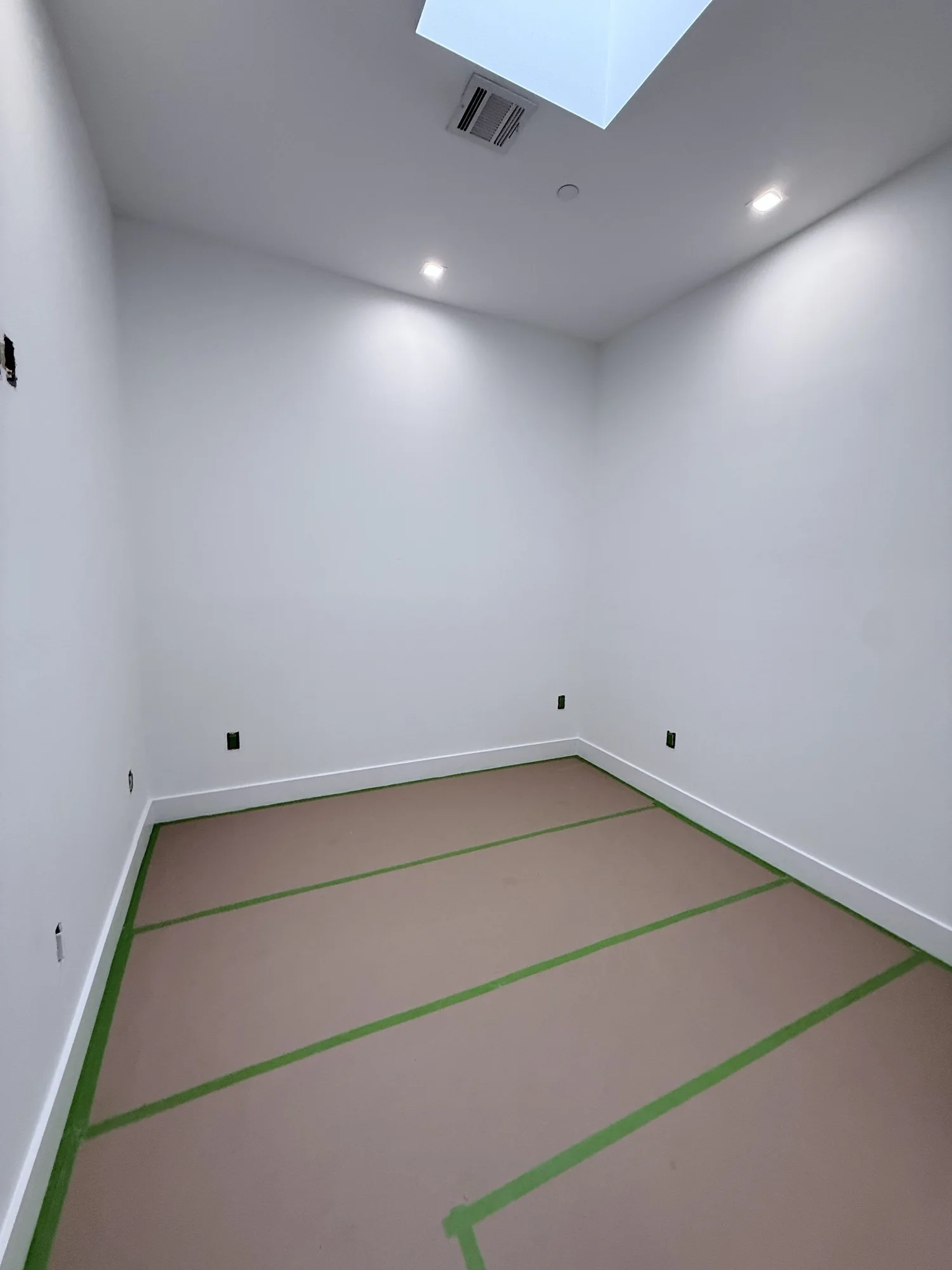 White room being masked off with tape and paper before painting black