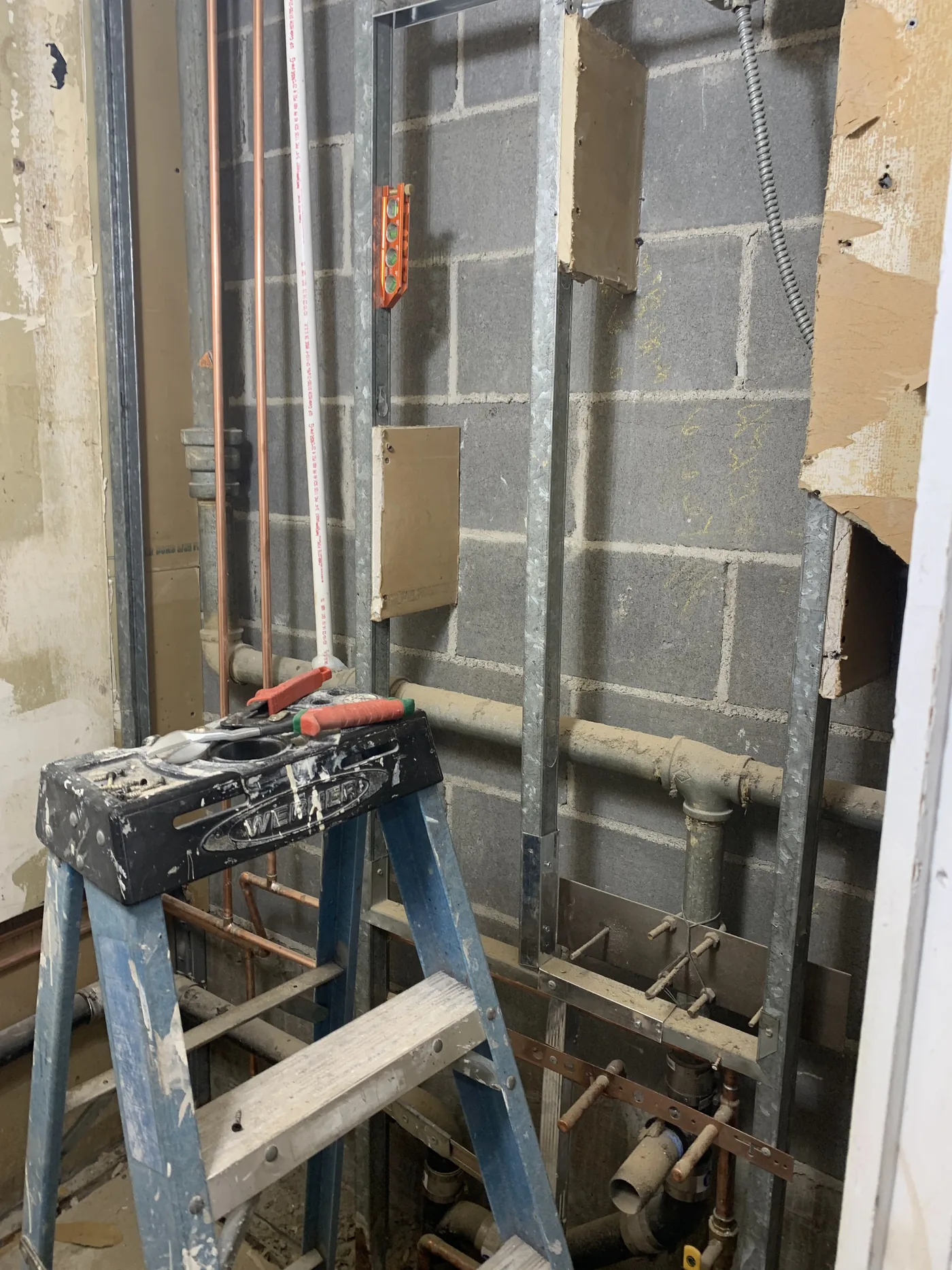 Old damaged drywall and exposed rough-in conditions before the barbershop build-out