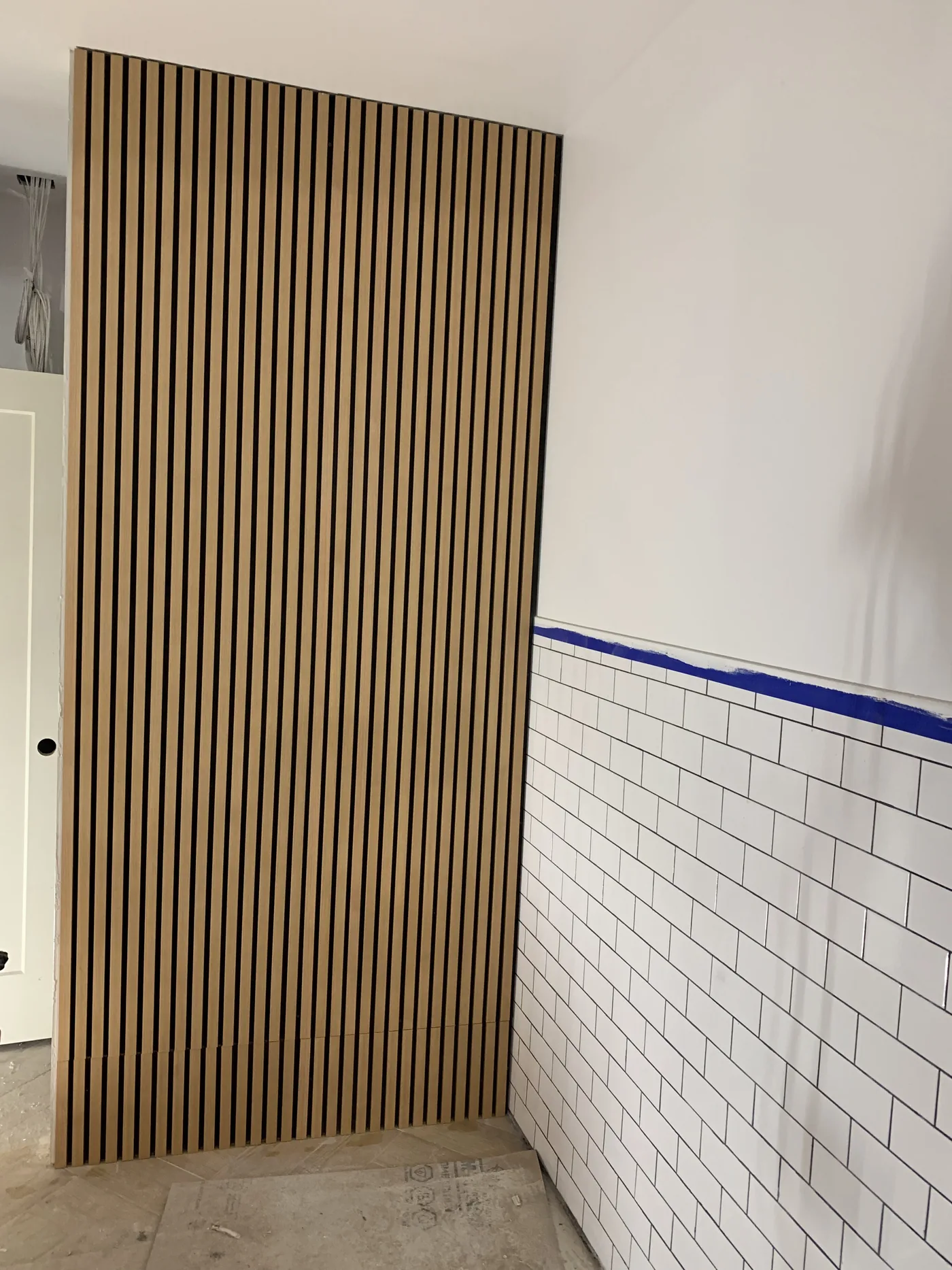 Custom drywall partition finished with vertical wood slat panels