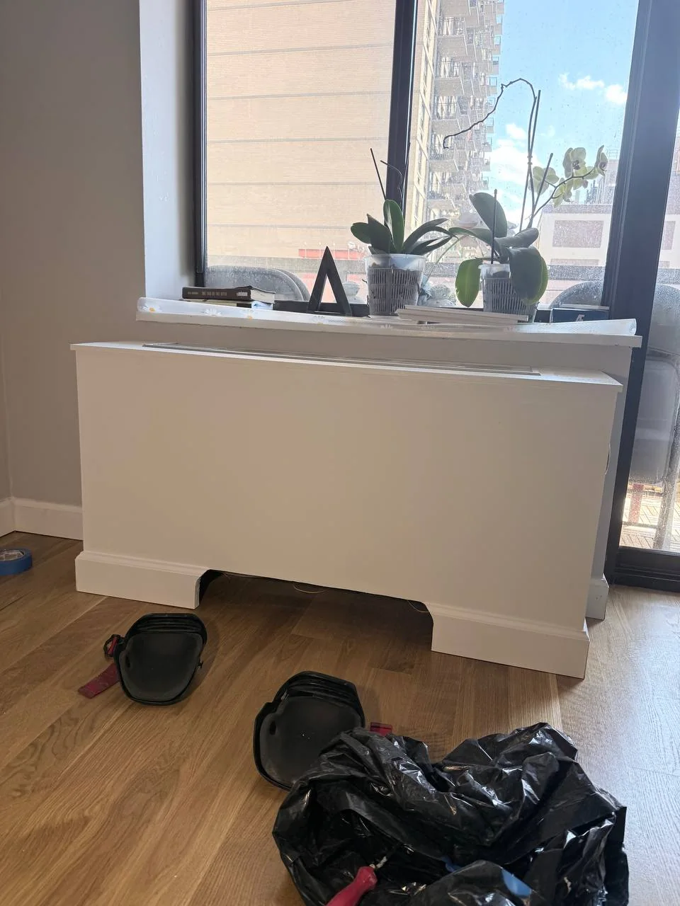 Finished custom white AC cover box under the window with orchids on the sill, NYC high-rise apartment