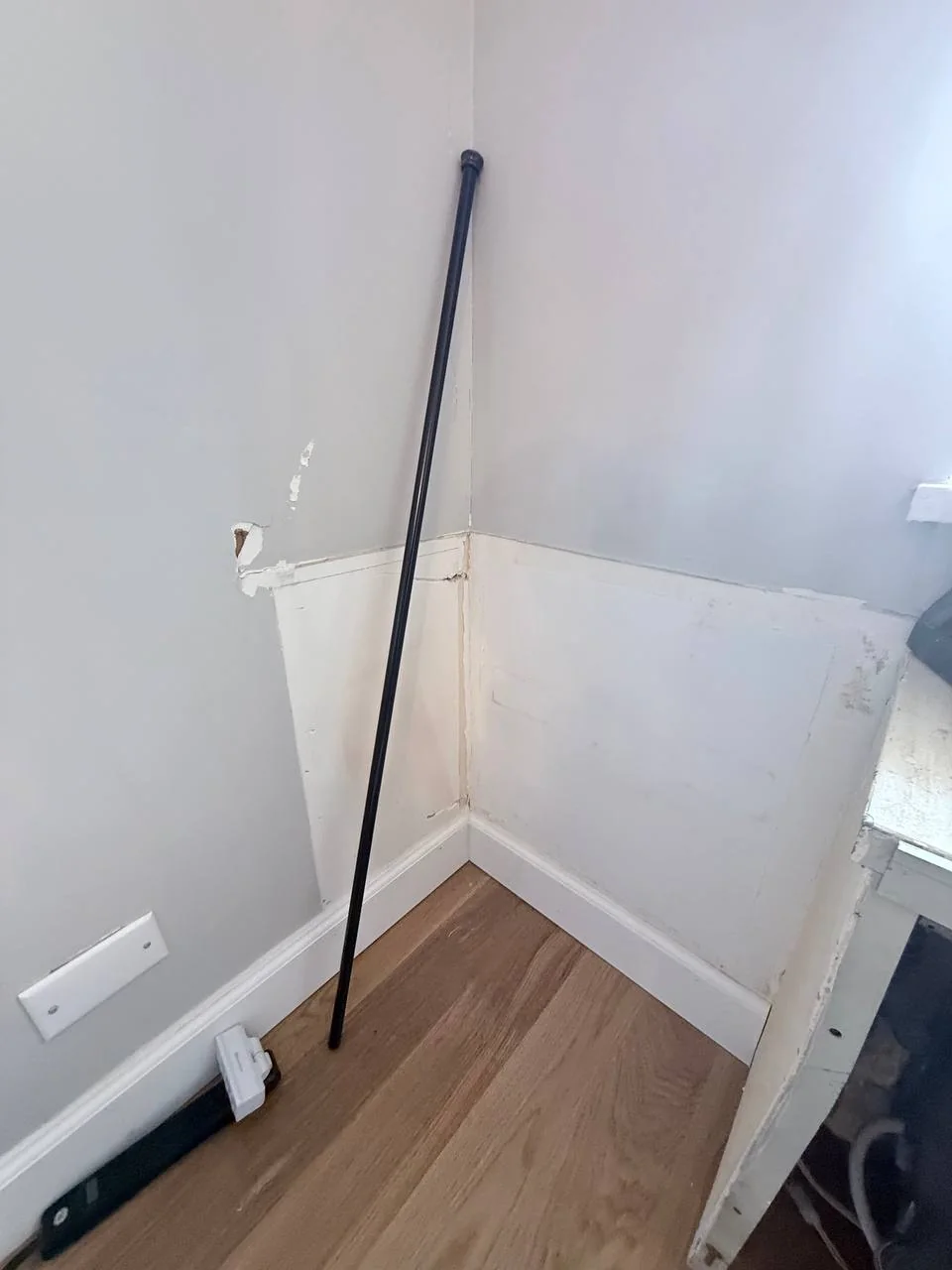 Flood-damaged corner of a wall with the lower drywall stripped and holes in the wall, NYC high-rise apartment