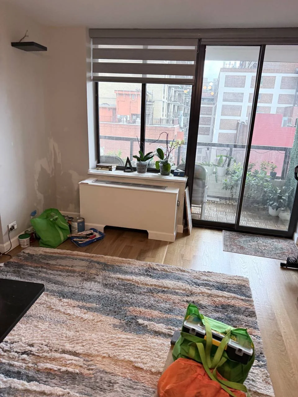 Living room with the new AC cover box under the window and patched walls before painting, NYC high-rise apartment