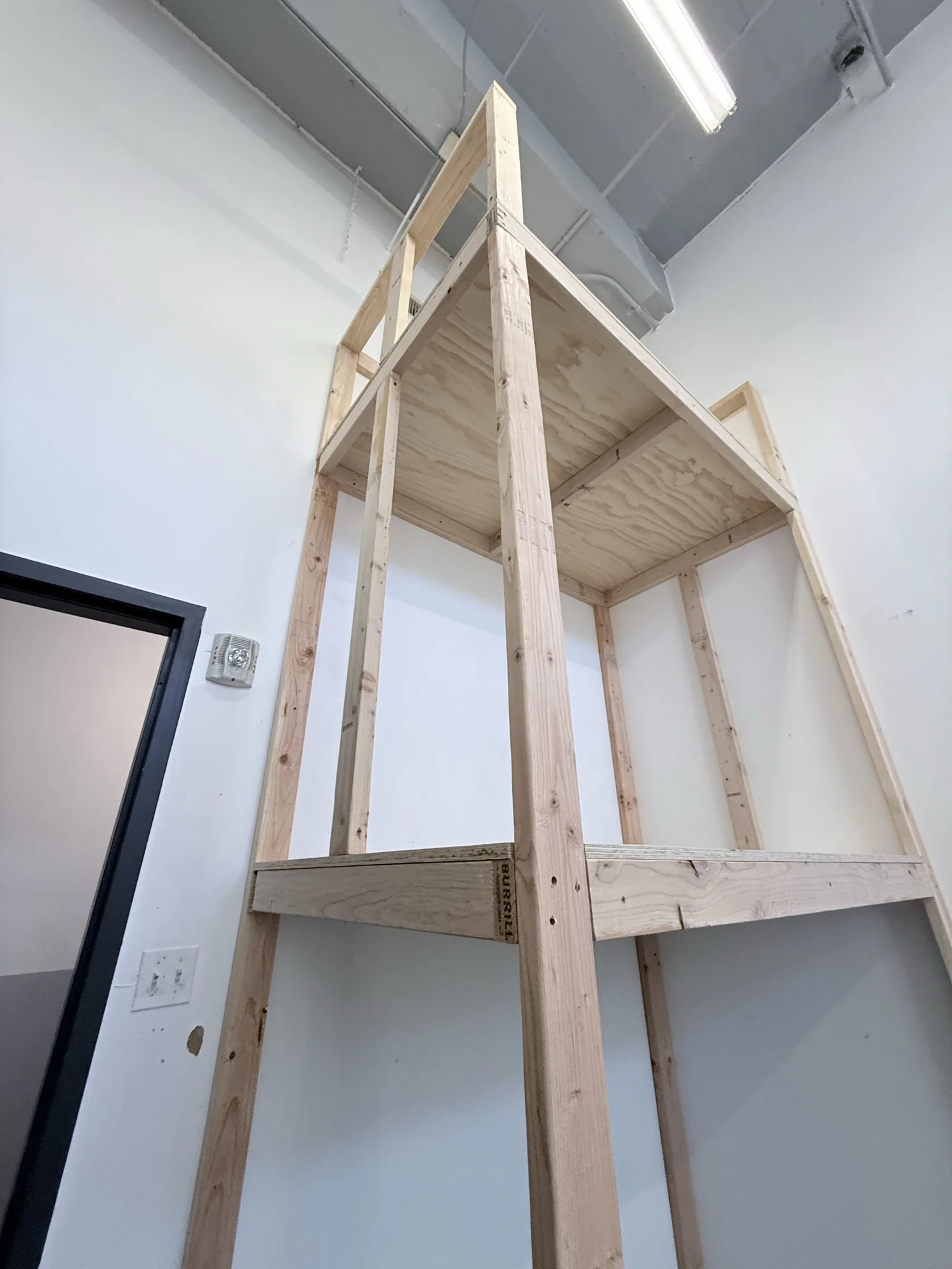 Low-angle view of the finished 2x4 and plywood storage rack showing its depth and both shelves