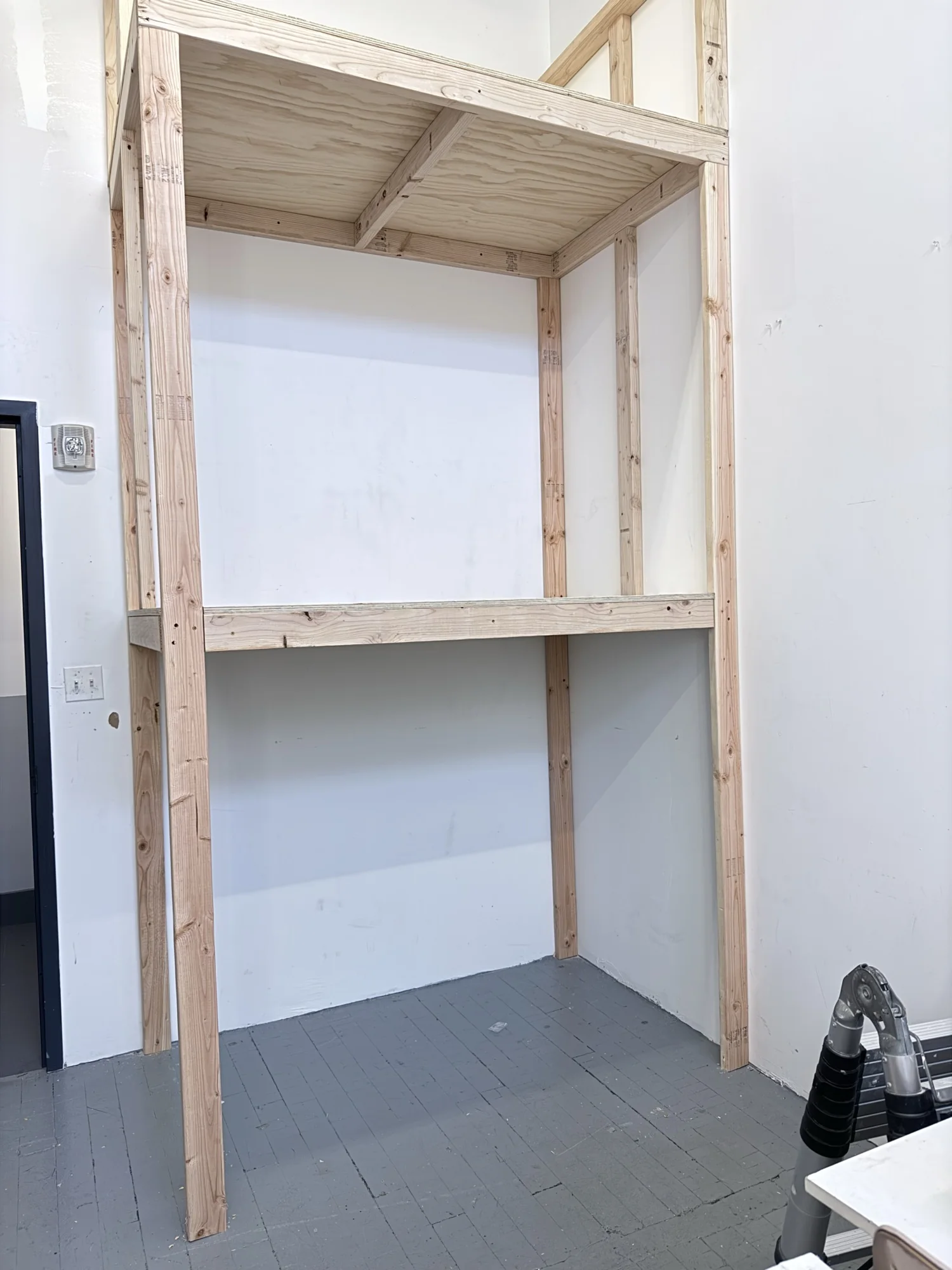Front view of the finished rack showing the two plywood shelf levels and the open bay at floor level