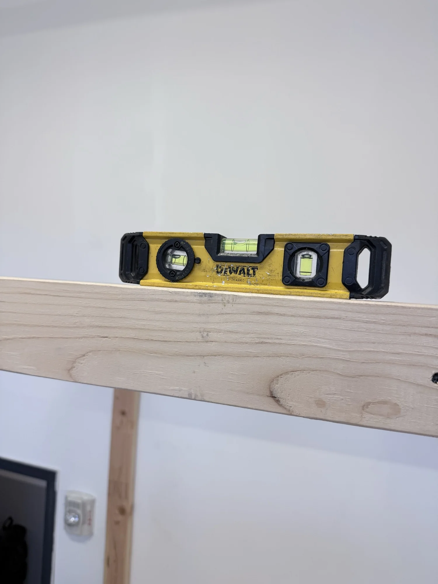 Small level sitting on a 2x4 rail of the storage rack during assembly
