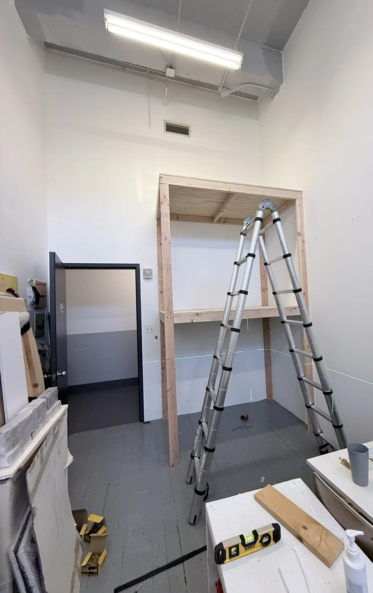 Storage rack frame standing with both shelves in and a ladder in front, during assembly