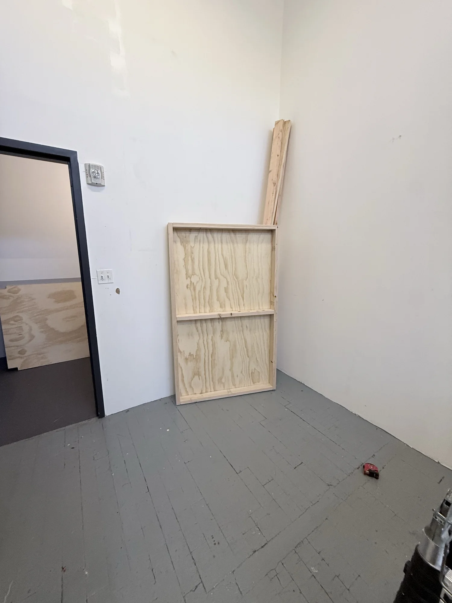 Assembled plywood shelf frame leaning against the studio wall before installation