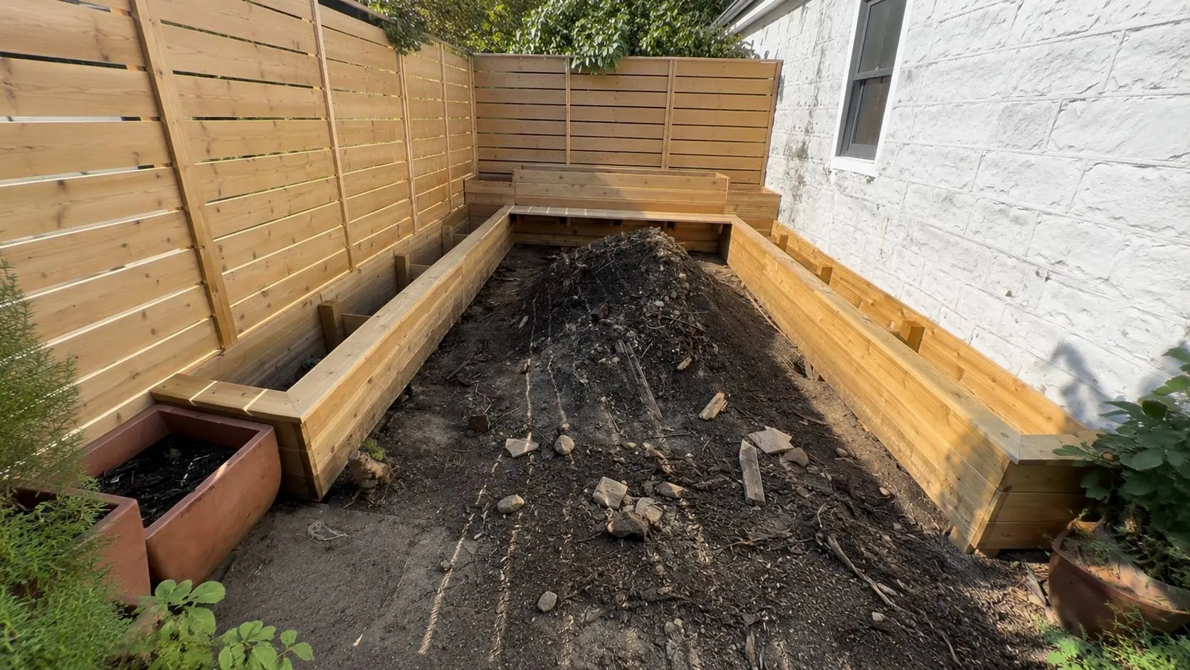 Wooden planter shell assembled around a center soil pile before cleanup