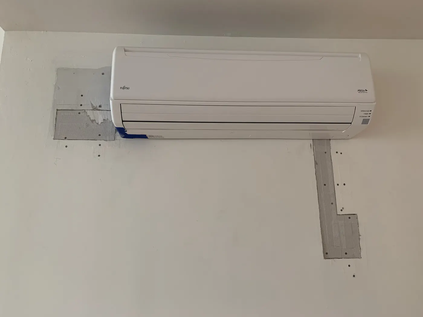 Joint compound progress on drywall repair below mini-split AC unit