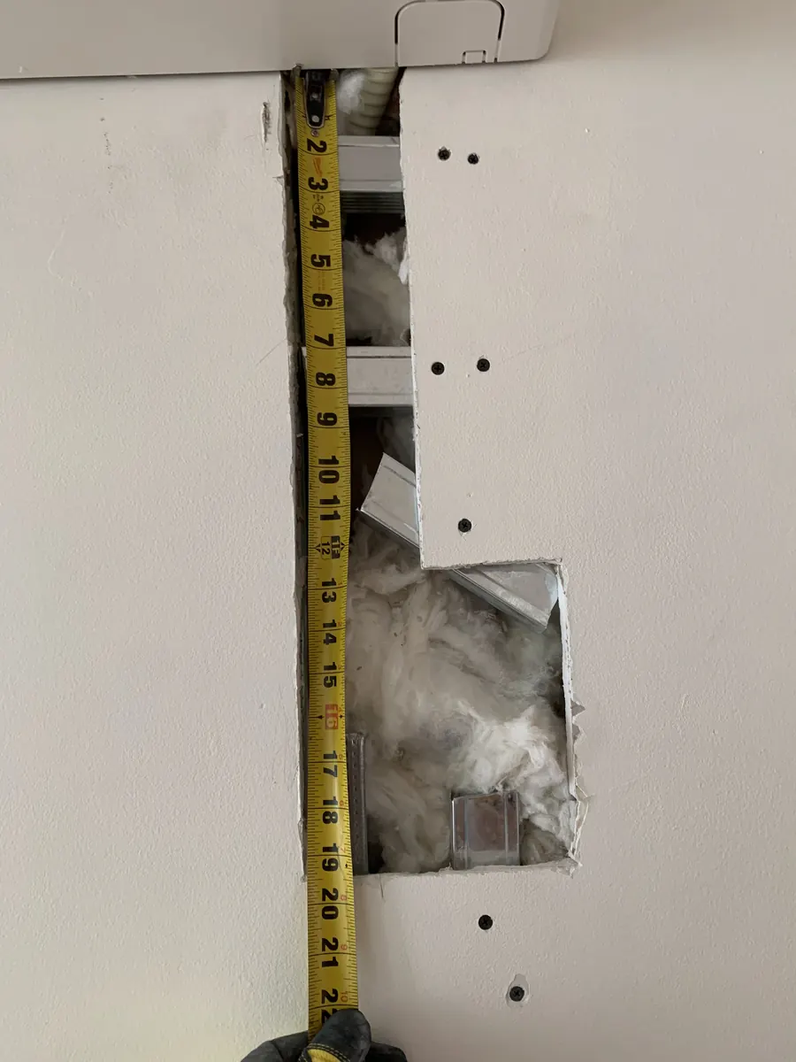 Measuring the drywall opening around mini-split lines before patching