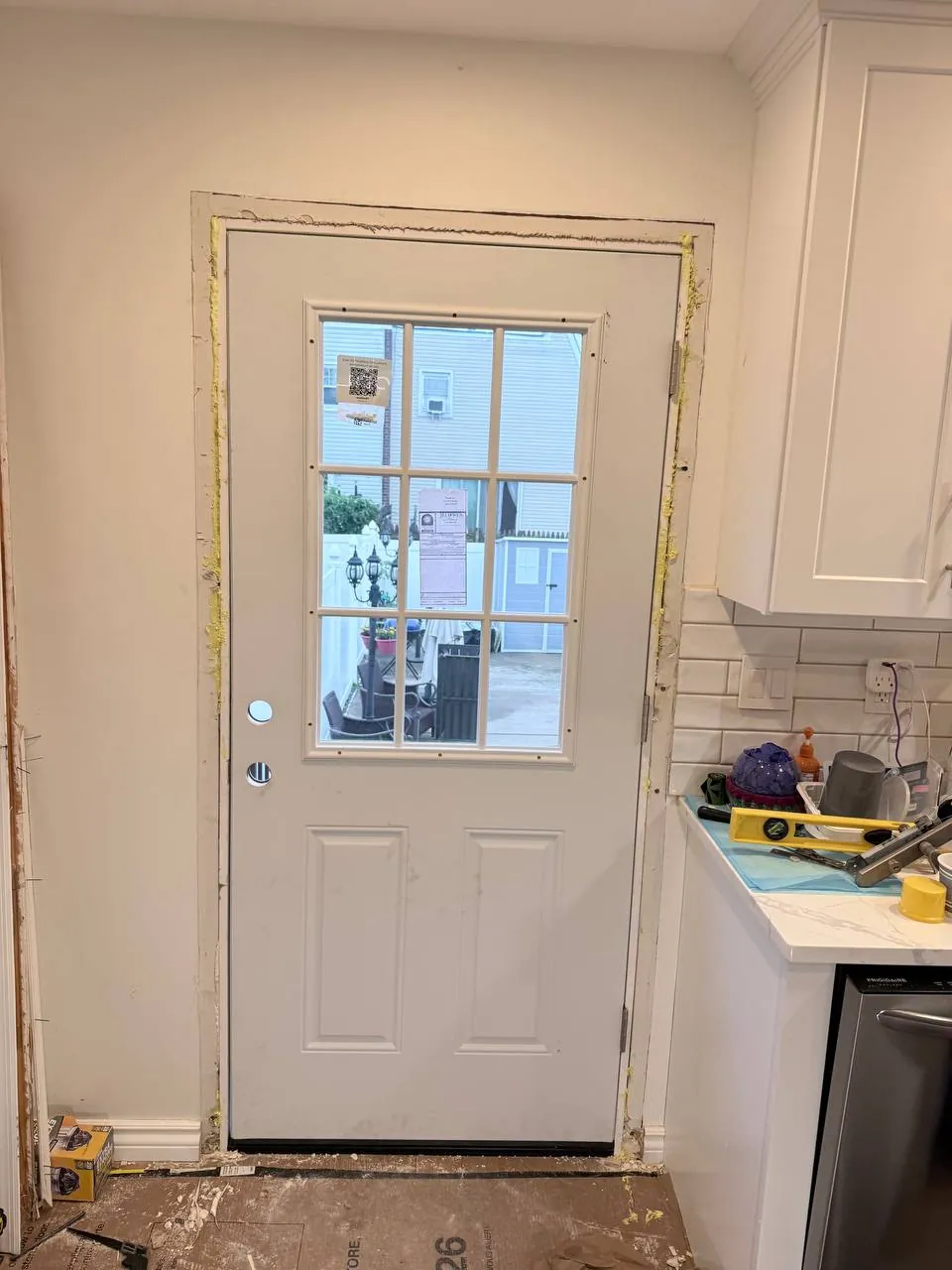 New entry door hung with spray foam sealing the frame and a cover plate over the unused lock bore