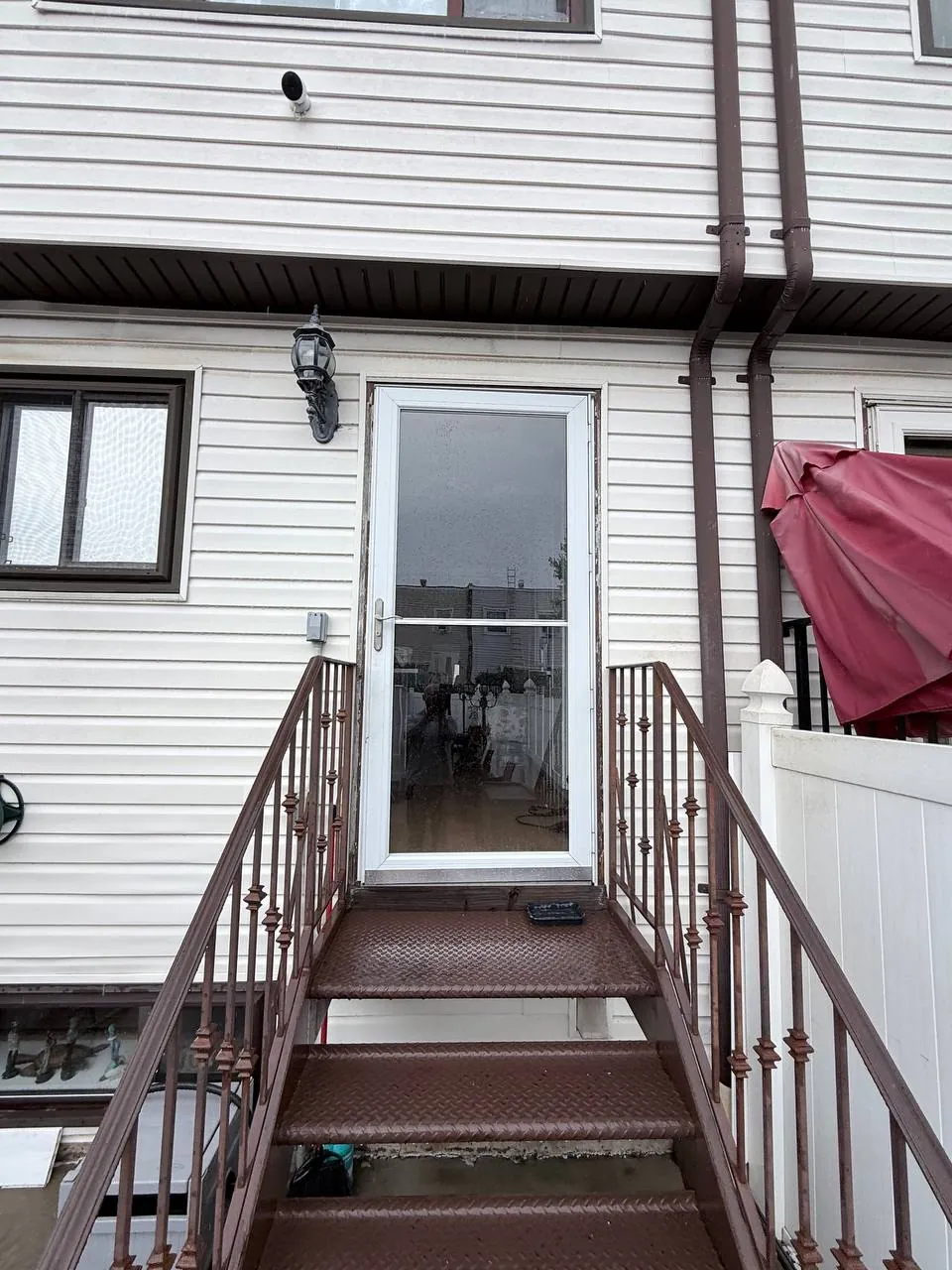 Old aluminum storm door at a Staten Island rear entry before replacement