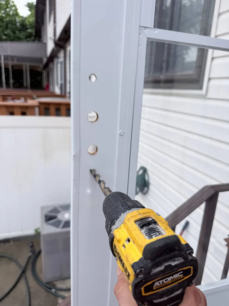 Drilling four template-marked holes for the additional storm door lock