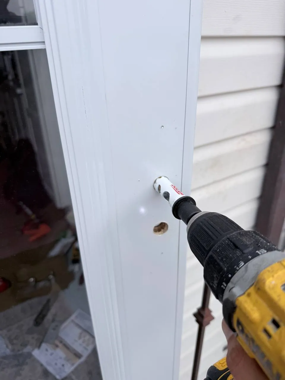 Cutting the additional lock opening in the storm door with a hole saw
