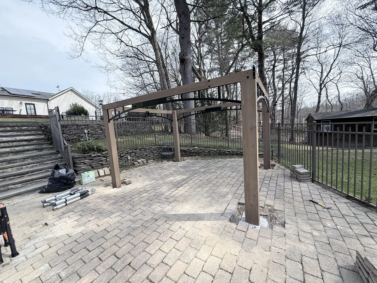 Gazebo frame with posts and top beams assembled on the paver patio before the roof