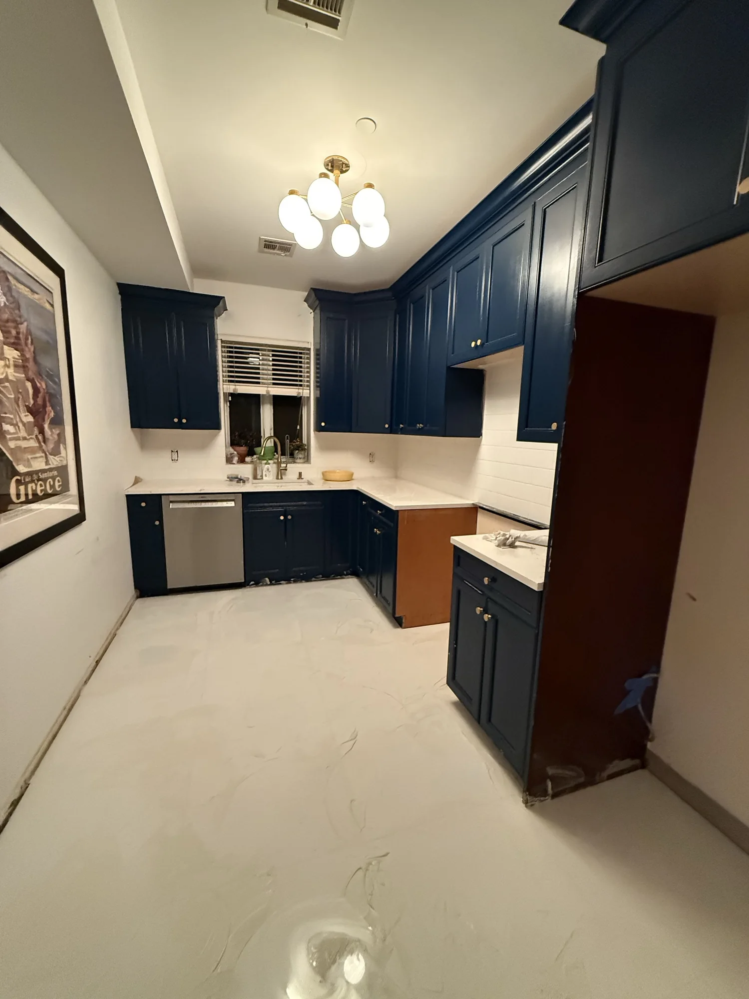 The same galley kitchen with navy cabinets, white subway tile backsplash and a new porcelain floor