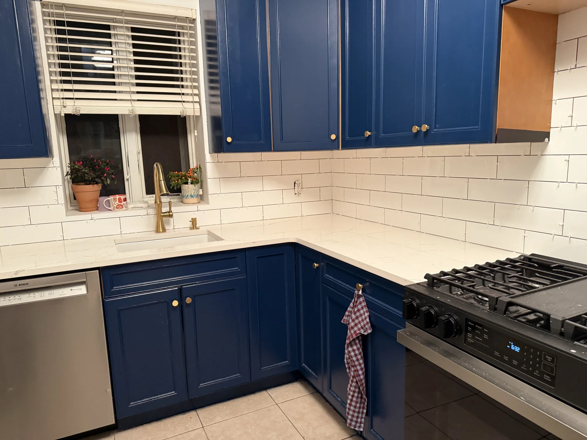 Finished white subway tile backsplash around the window and sink with navy cabinets