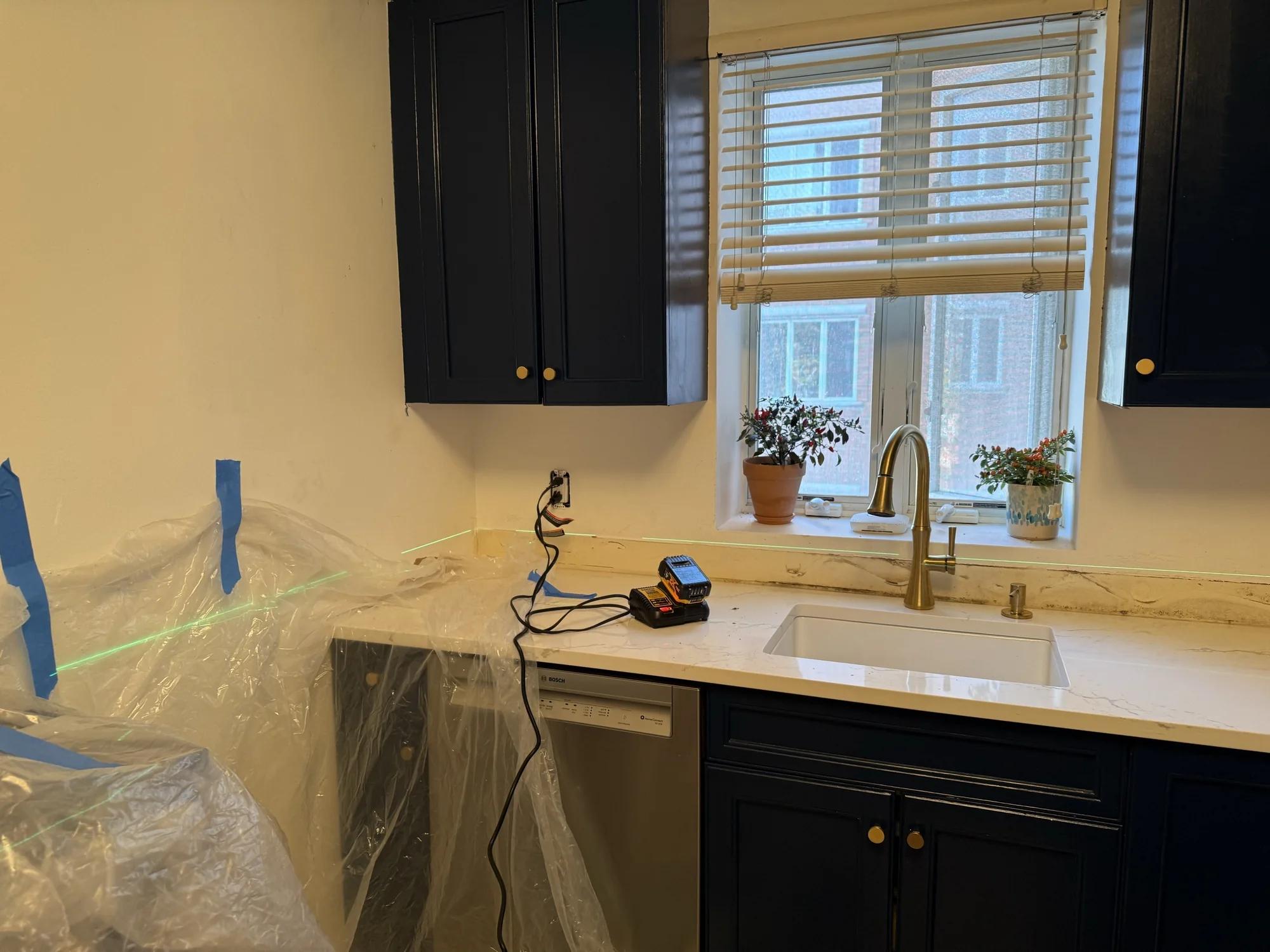 Laser line across the wall by the sink and window, countertop covered and taped for tiling