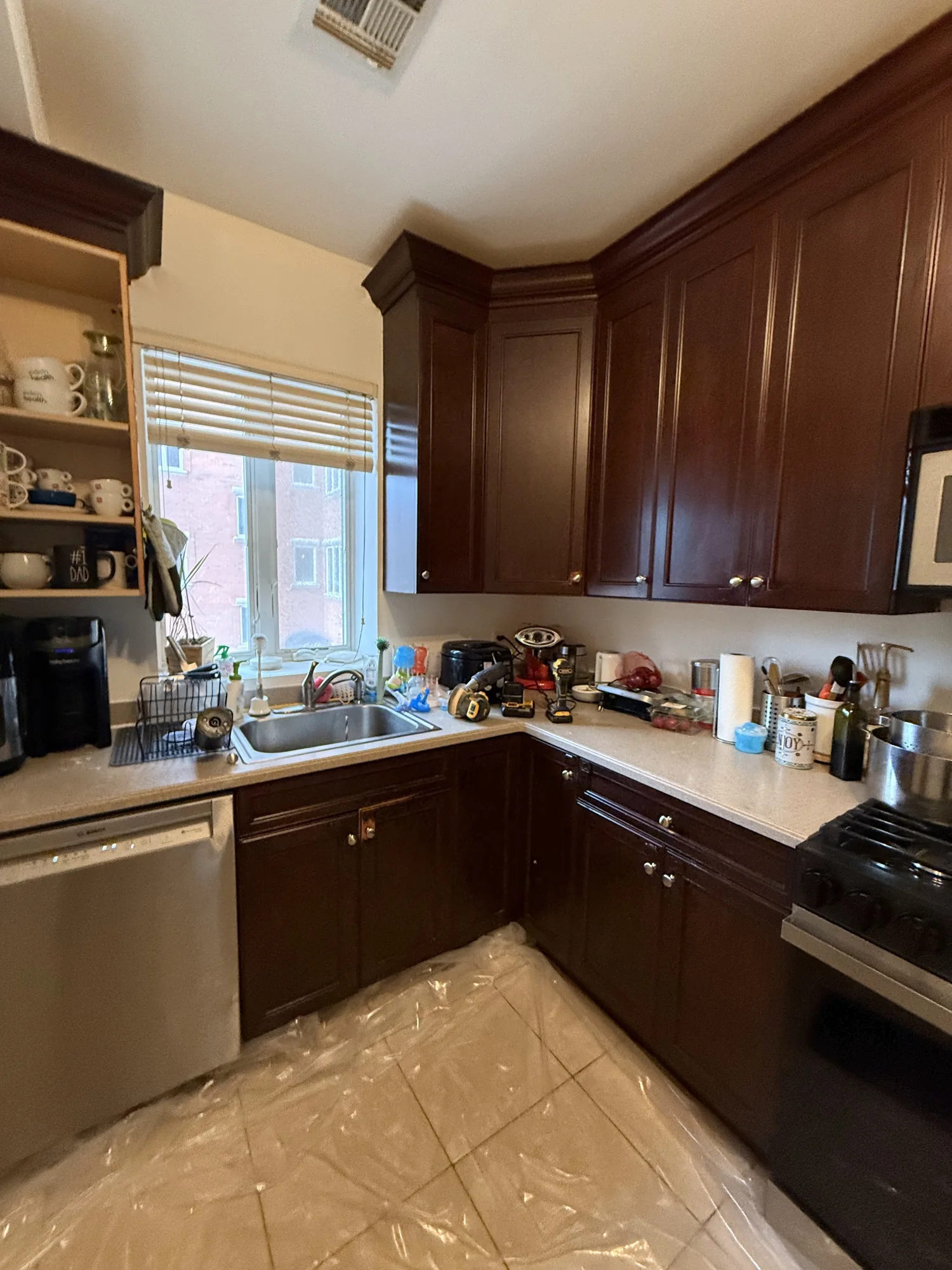 Kitchen with brown cabinets and the floor covered in protective film before the work started