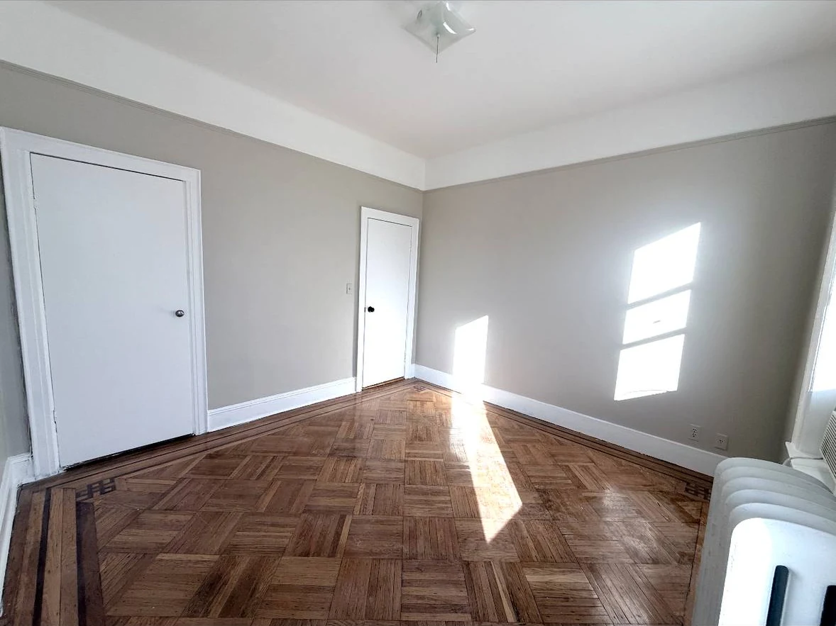 Bedroom after apartment turnover with fresh paint and refinished parquet floor