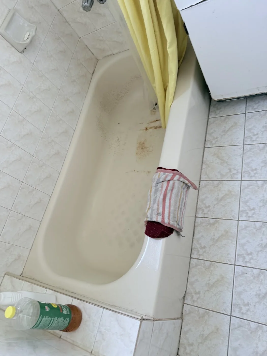 Bathroom before apartment turnover with stained tub and old curtain