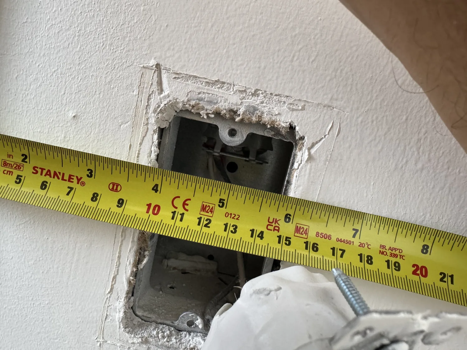 Open electrical outlet box measured before cutting plastic wall panel opening