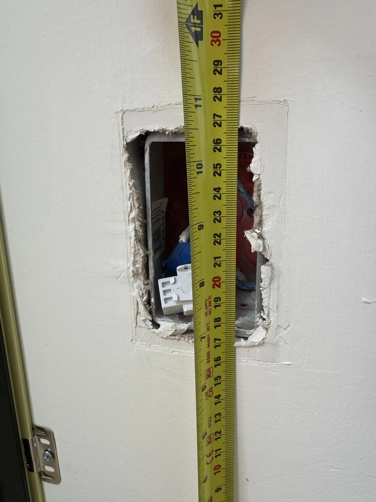 Vertical tape measurement at an outlet opening before wall panel installation