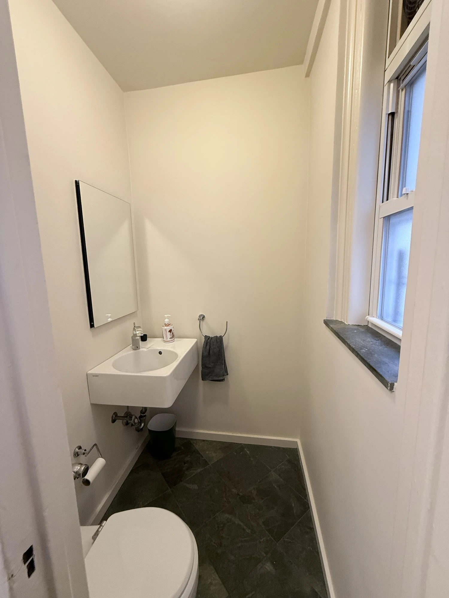 Small all-white powder room with sink, mirror, toilet and window before the makeover, Upper West Side Manhattan