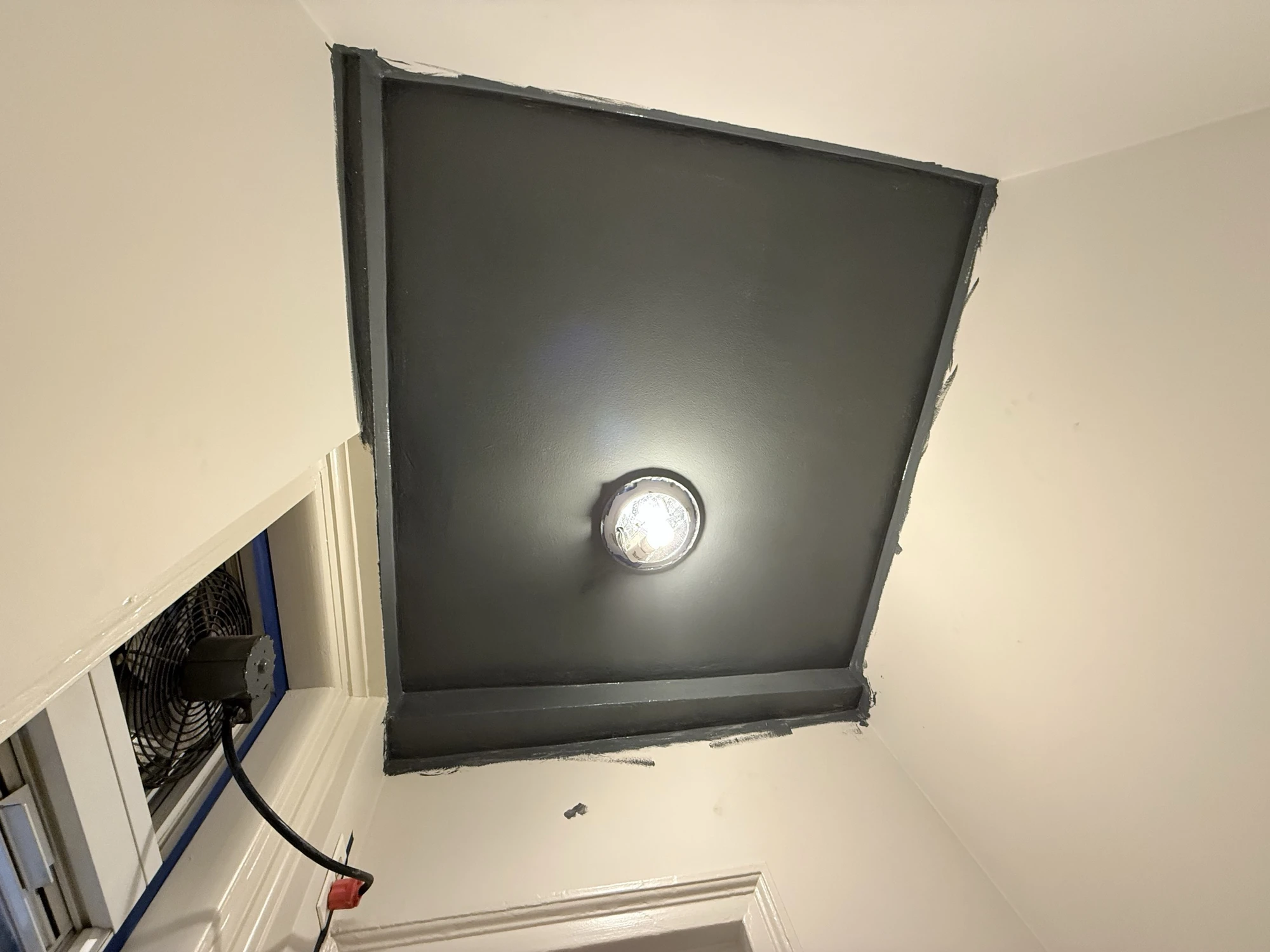 Powder room ceiling painted a deep dark color around the ceiling light