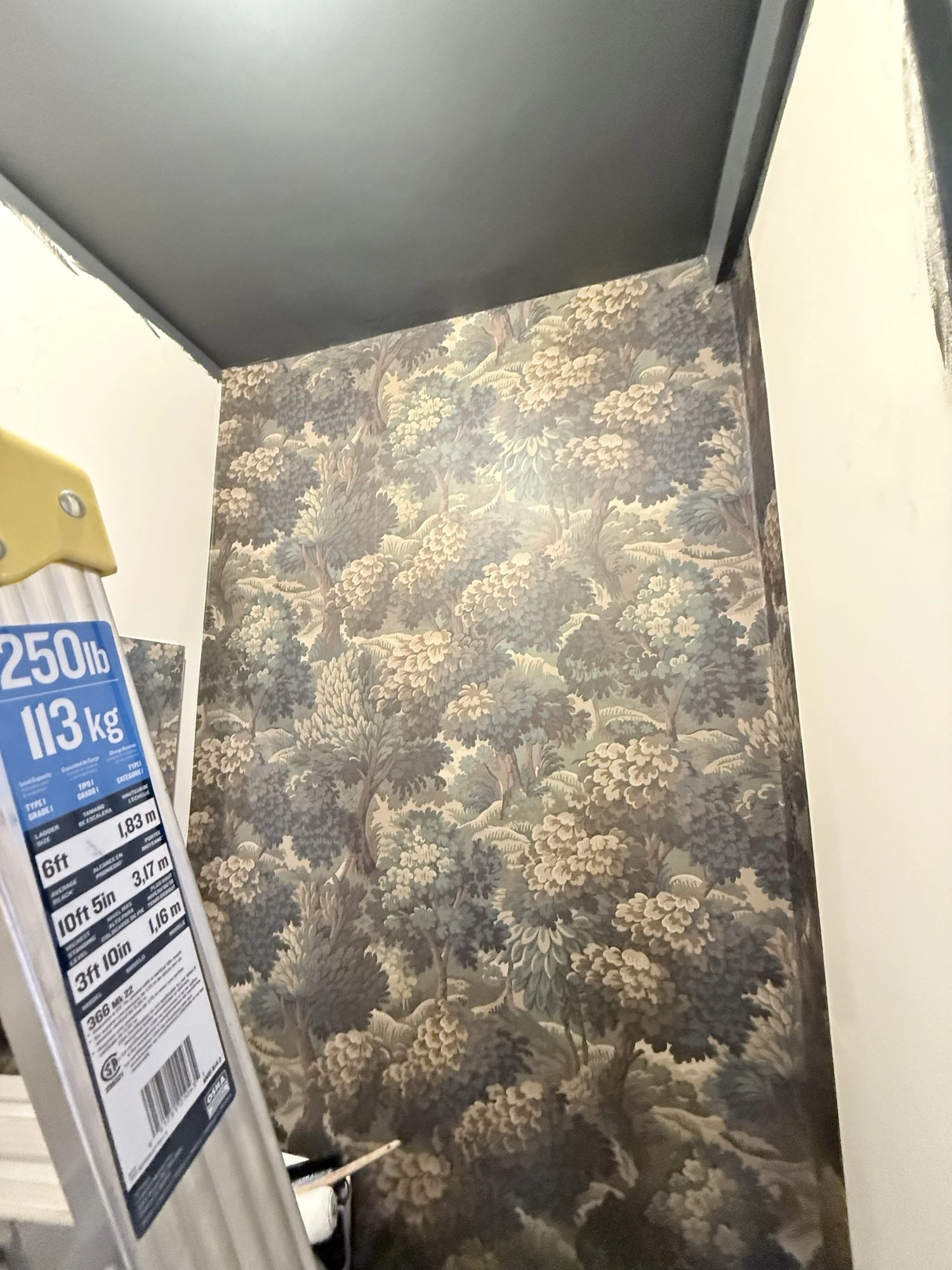 Large botanical wallpaper being hung on the powder room wall