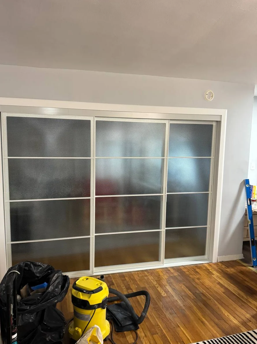 Three sliding textured-glass doors closed in a white cased opening, DUMBO Brooklyn apartment