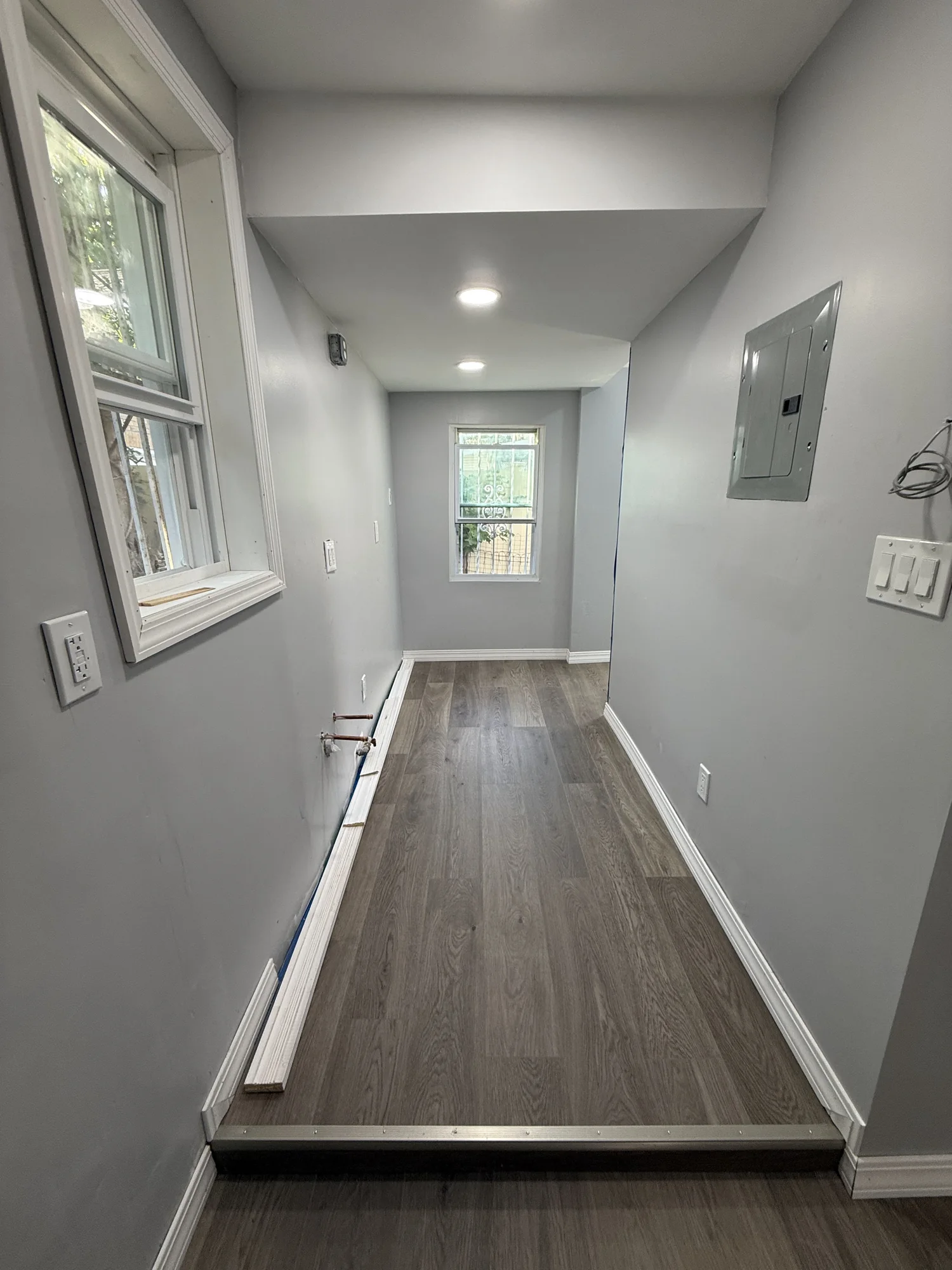 The same hallway with the finished vinyl plank floor, new baseboards and window casing