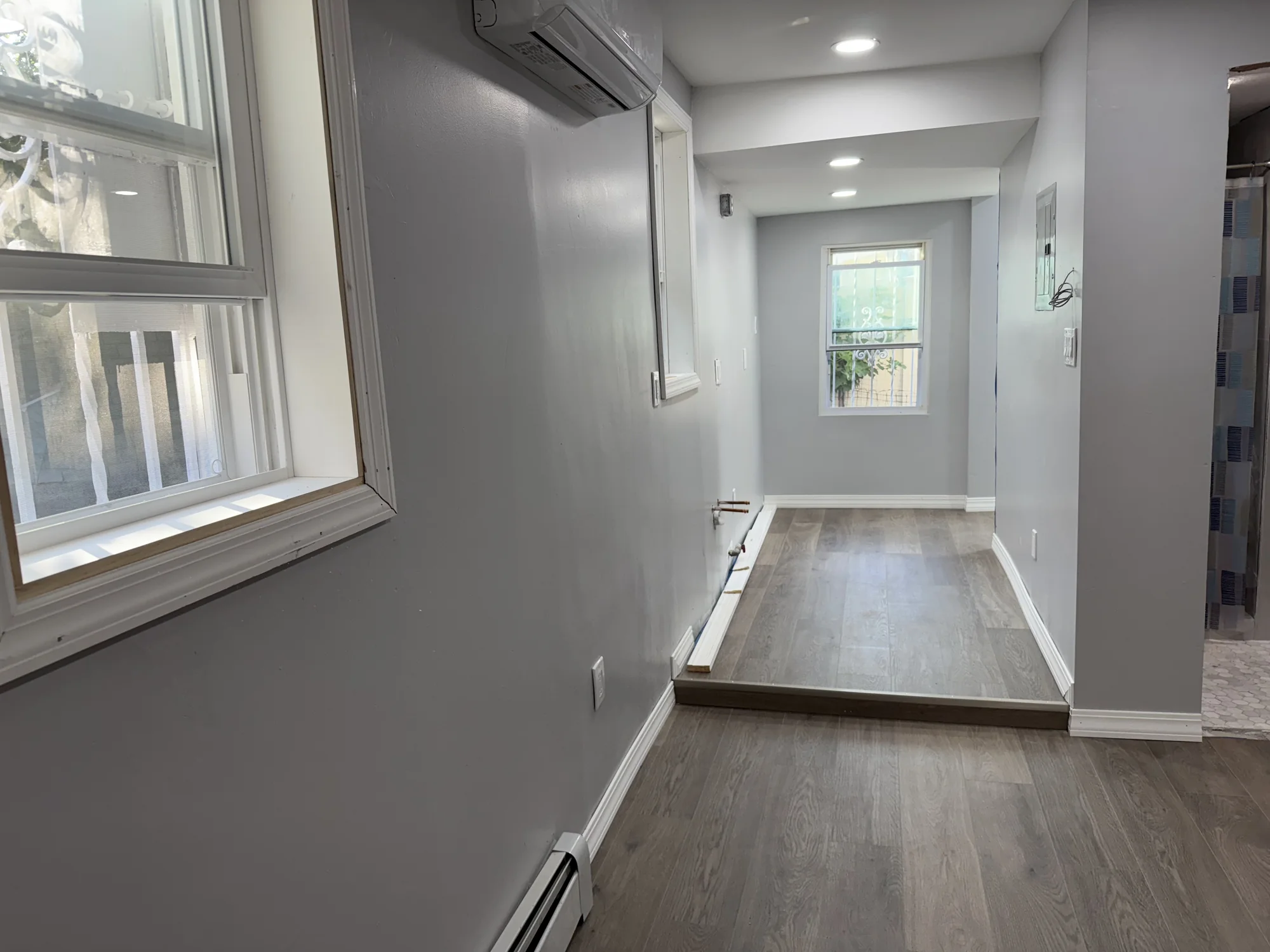 Hallway with the new vinyl plank floor and window casing, looking toward the door