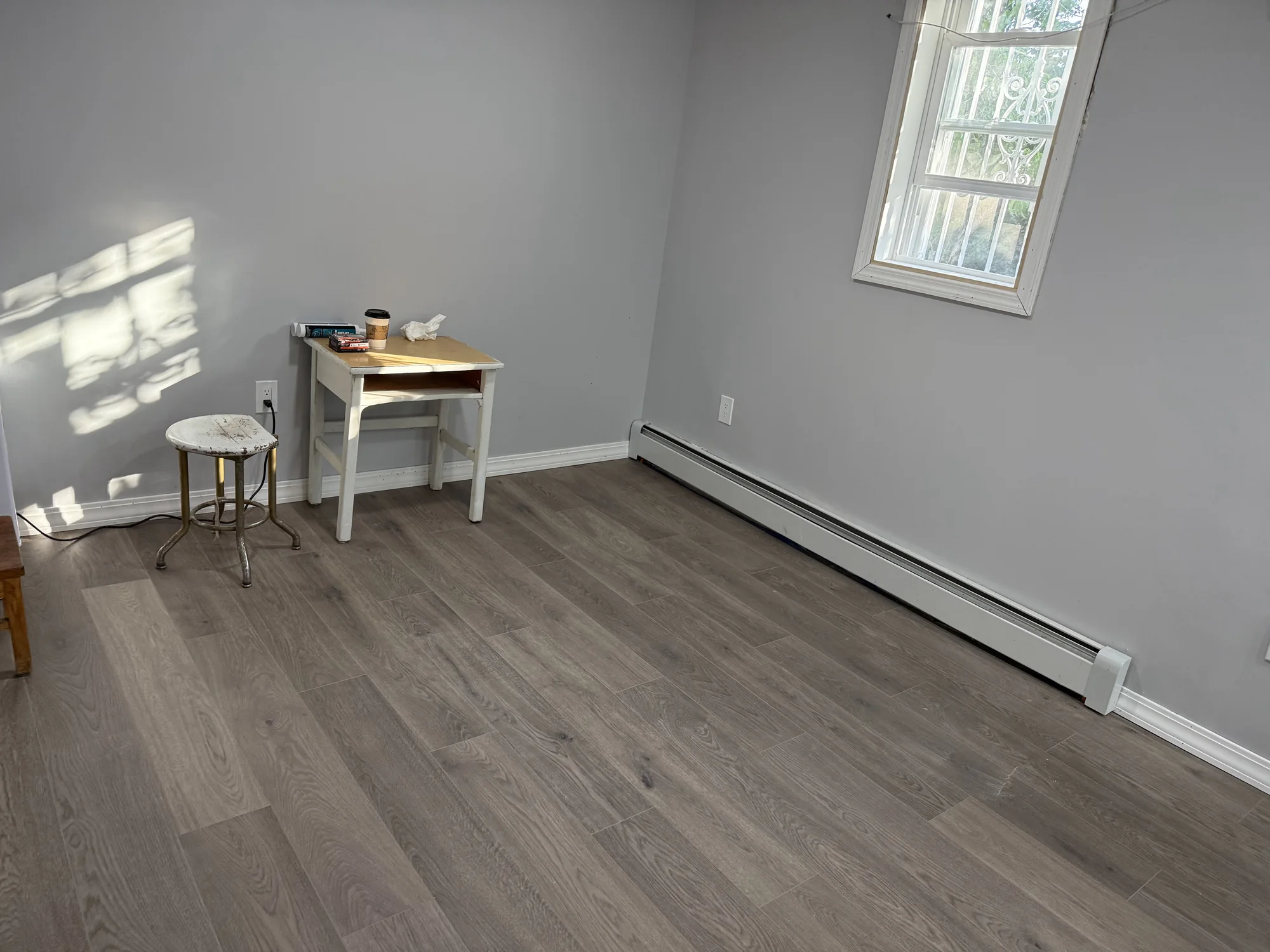 Finished vinyl plank floor with new white baseboard and window casing