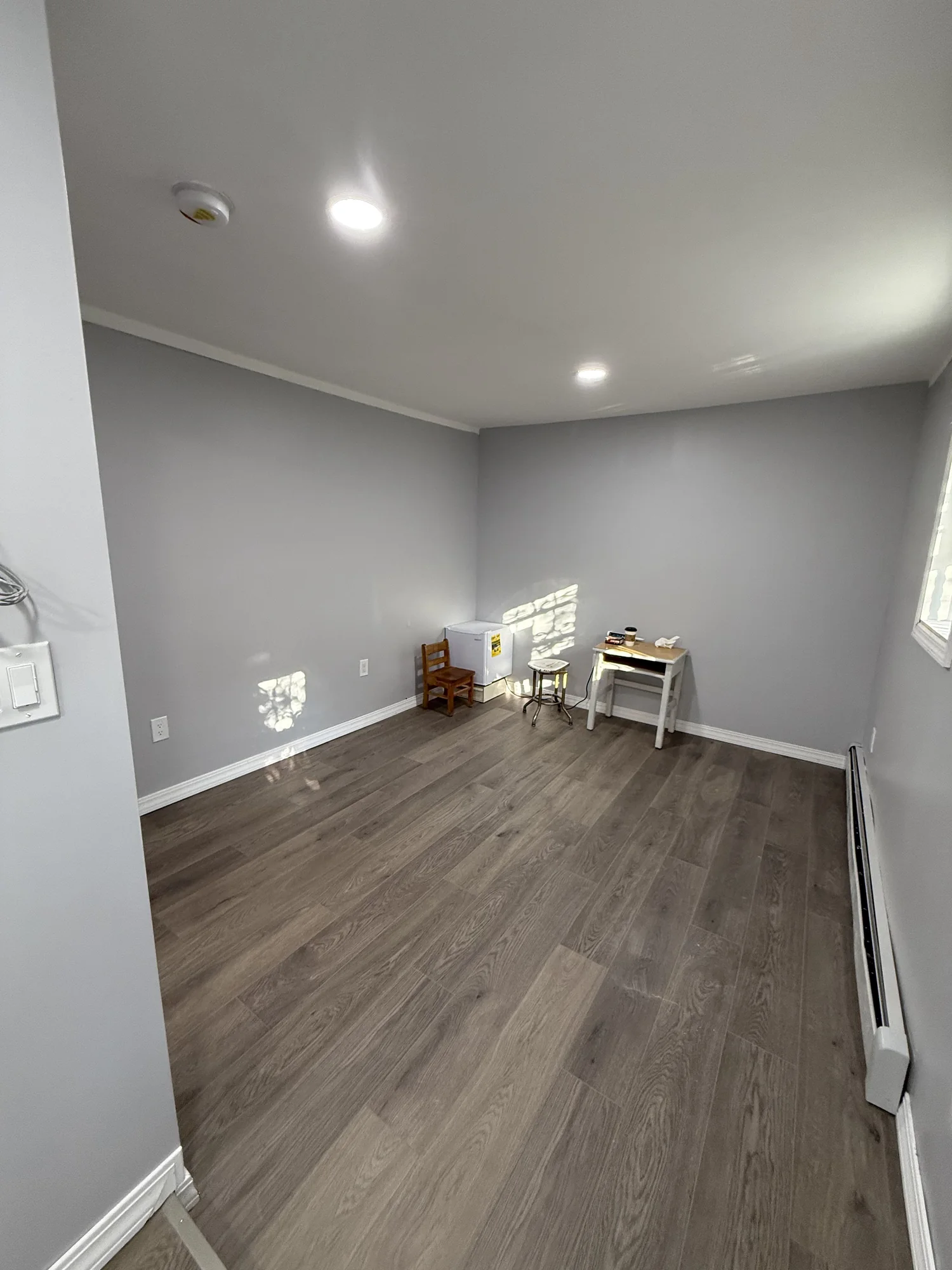 Finished room with grey-brown vinyl plank floor and white baseboards, Hollis Queens