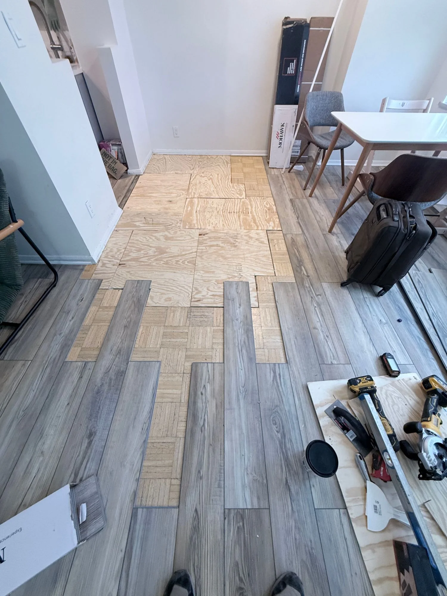 New vinyl planks being laid over the plywood subfloor, Bronx apartment living room