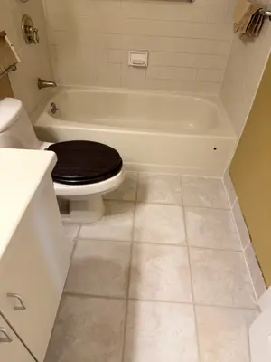 completed bathroom tile flooring installation with clean grout lines and updated baseboard in nyc