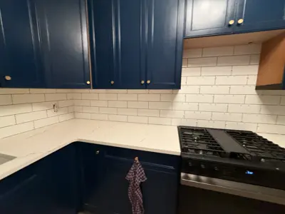 completed kitchen renovation with navy blue painted cabinets and white subway tile backsplash in nyc