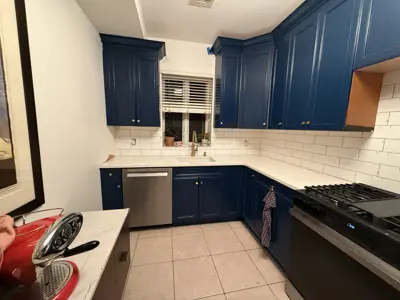 completed navy blue kitchen cabinet painting with white subway tile backsplash and stainless appliances in nyc home